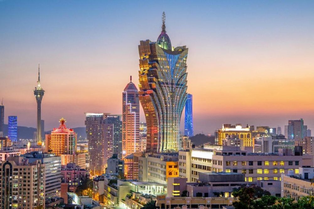 La torre del Grand Lisboa iluminada dominando el perfil de la peninsula al atardecer