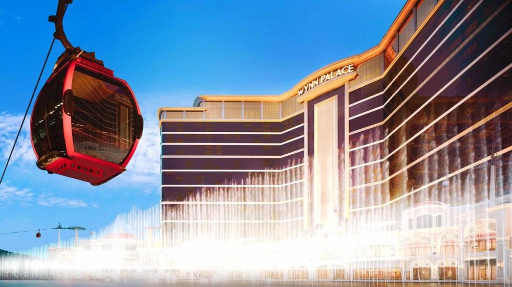 Fachada de Wynn Palace con el lago de surtidores en accion y una gondola aerea del SkyCab